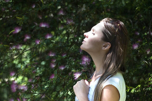 a woman closing her eyes meditating in nature