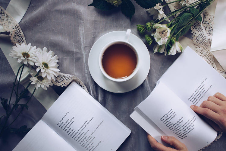 a person reading a book in a calming way with a cup of hot drink on the table